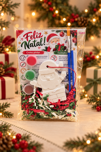 Kit Artes M com Pai Natal a acenar para pintar em gesso branco, três tintas e dois pincéis, em embalagem transparente.